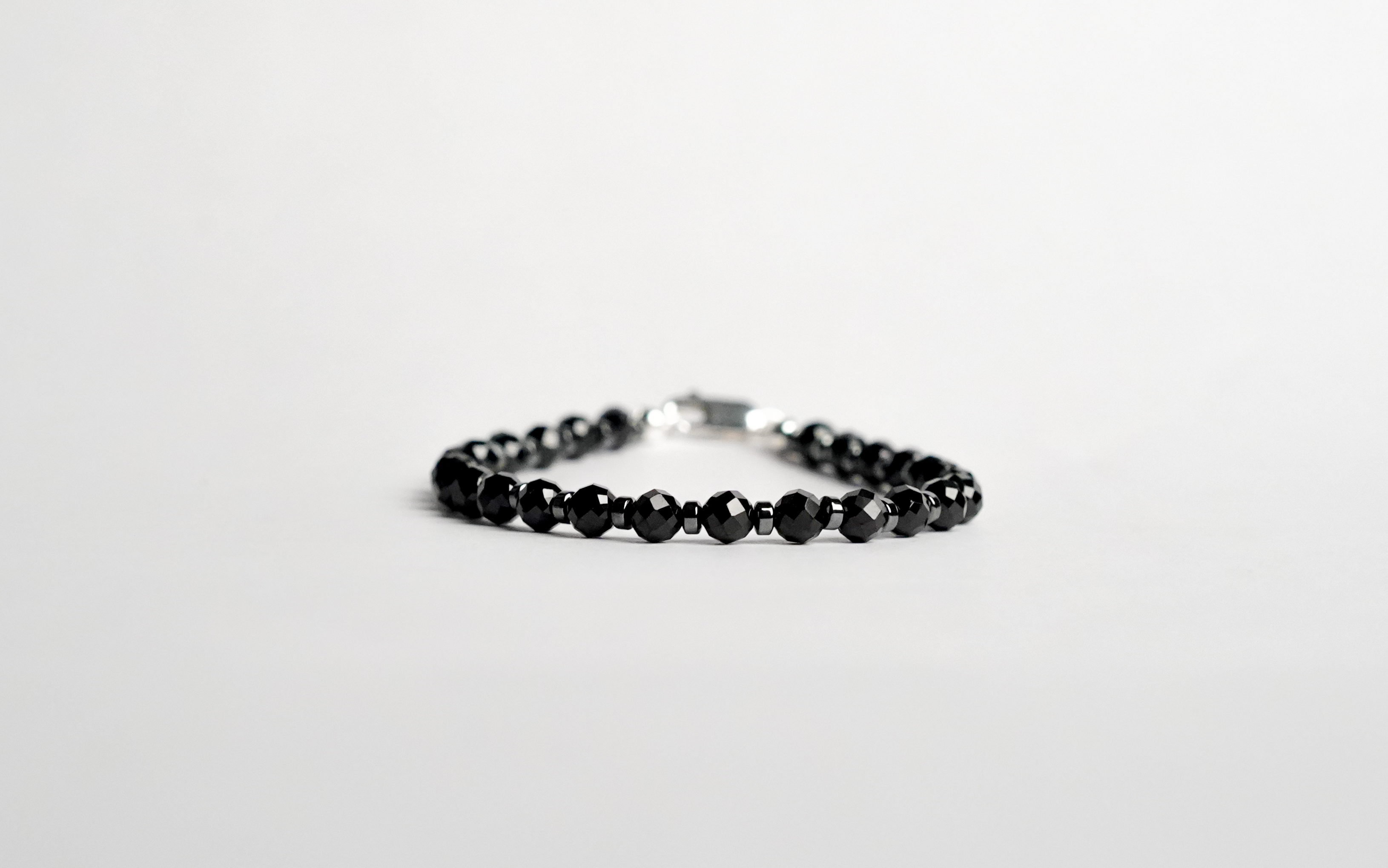 Il bracciale è realizzato con perle sfaccettate di Spinello nero ed ematite. Rifinito con accenti in Argento sterling 925 e pratica chiusura a moschettone in Argento sterling 925. Fatto completamente a mano in Italia.