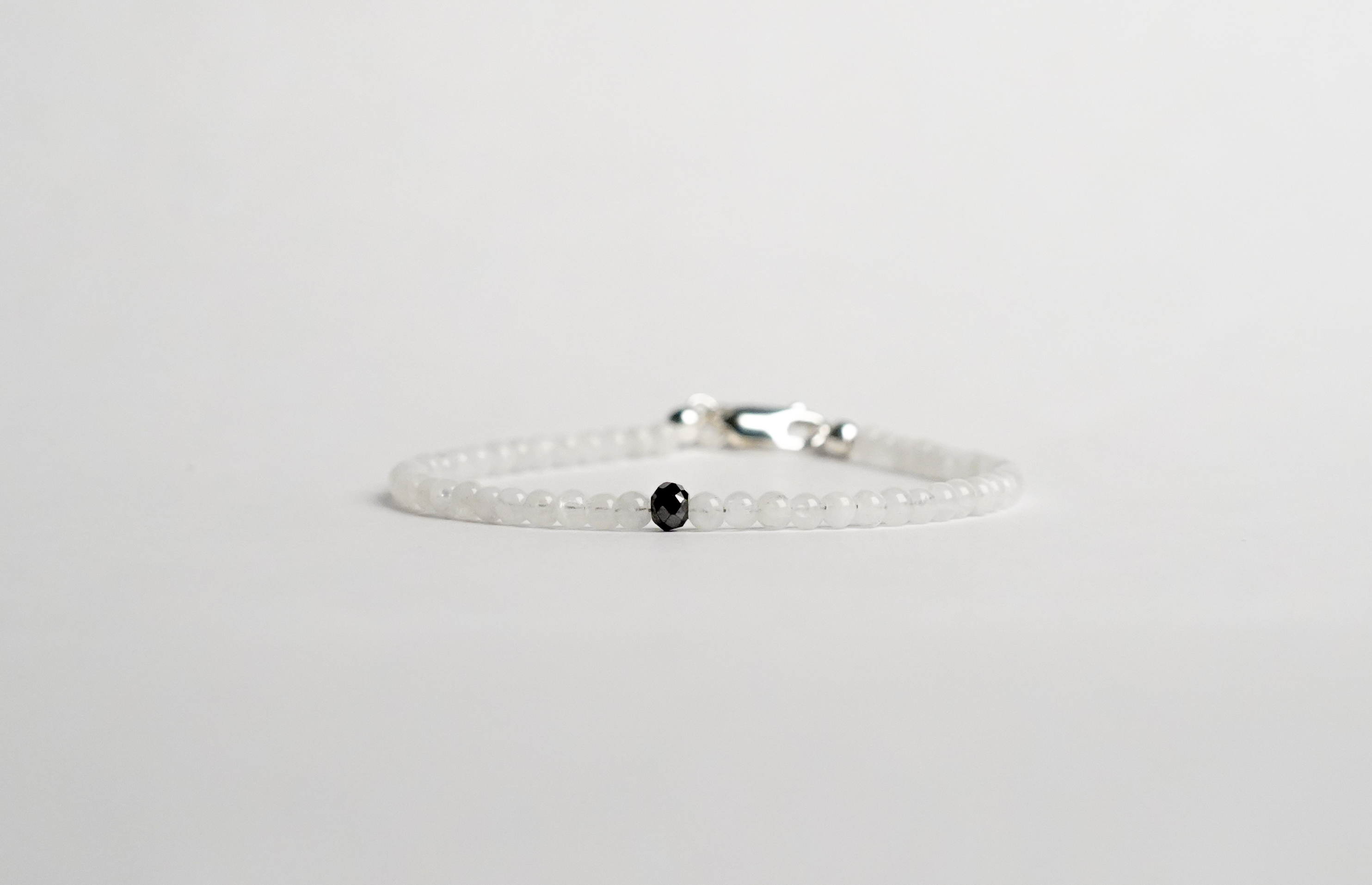 Il bracciale è realizzato con perle di Pietra di Luna bianche, Onice nero e gemma di Diamante nero. Rifinito con pratica chiusura a moschettone in Argento sterling 925. Un gioiello unico ed affascinante. Fatto completamente a mano in Italia.