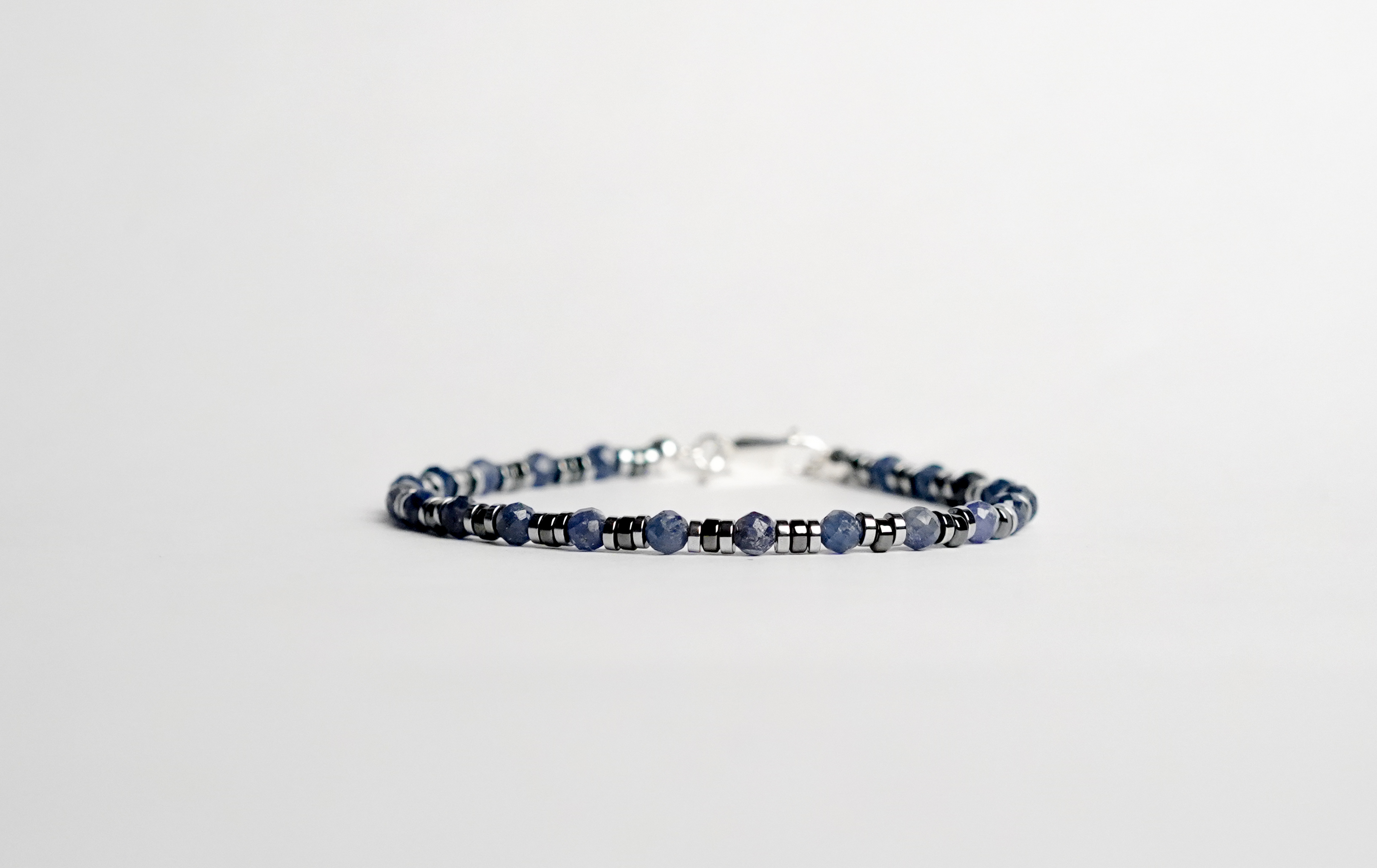 Il bracciale è realizzato con gemme di Zaffiro blu ed ematite. Rifinito con accenti in Argento sterling 925 e pratica chiusura a moschettone in Argento sterling 925. Fatto completamente a mano in Italia.