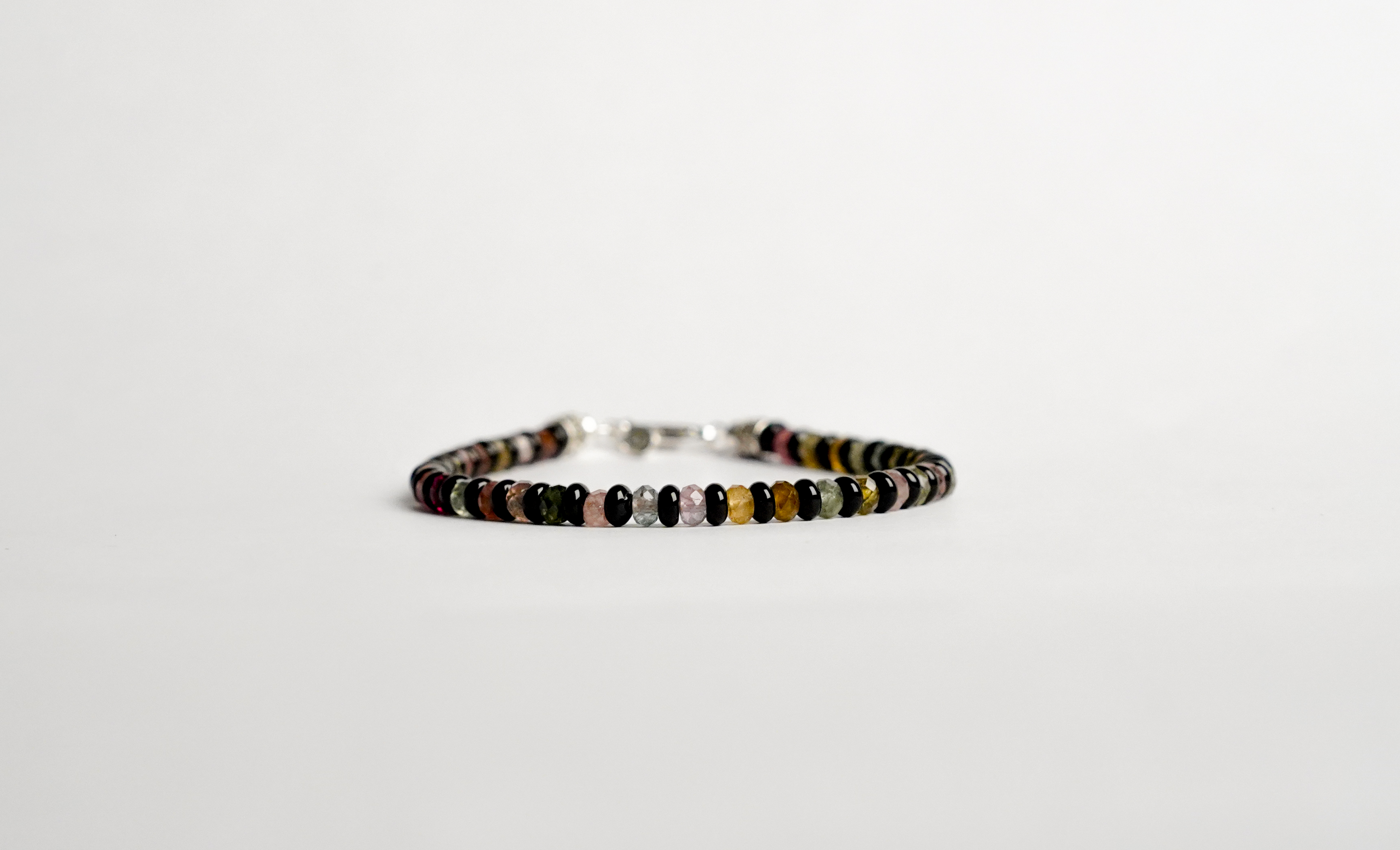 Il bracciale è realizzato con gemme di Tormalina multicolore, Onice nero e rifinito con accenti in Argento sterling 925 e pratica chiusura a moschettone in Argento sterling 925.