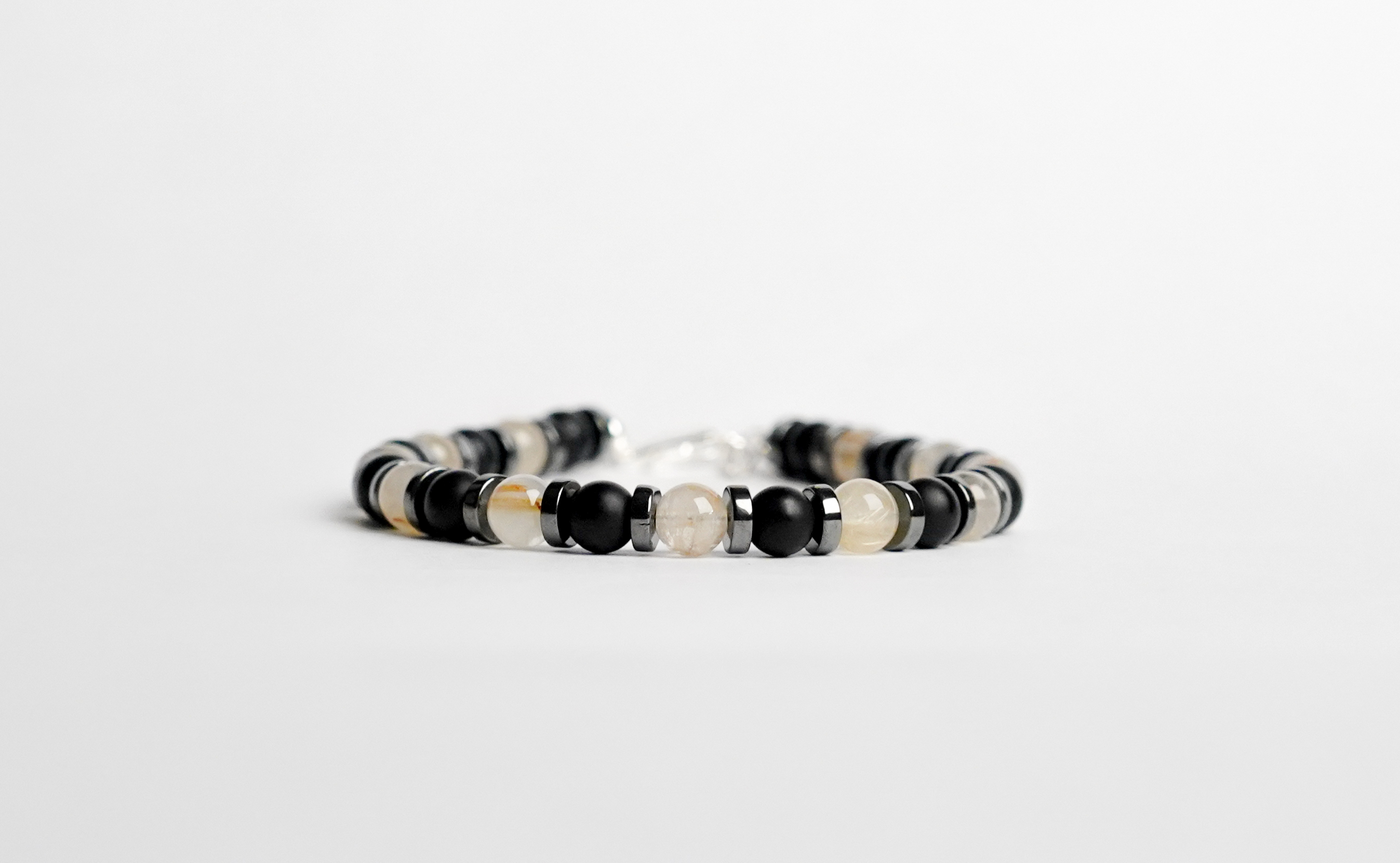 Il bracciale è realizzato con perle di Agata nera opaca, Quarzo rutilato oro ed ematite.