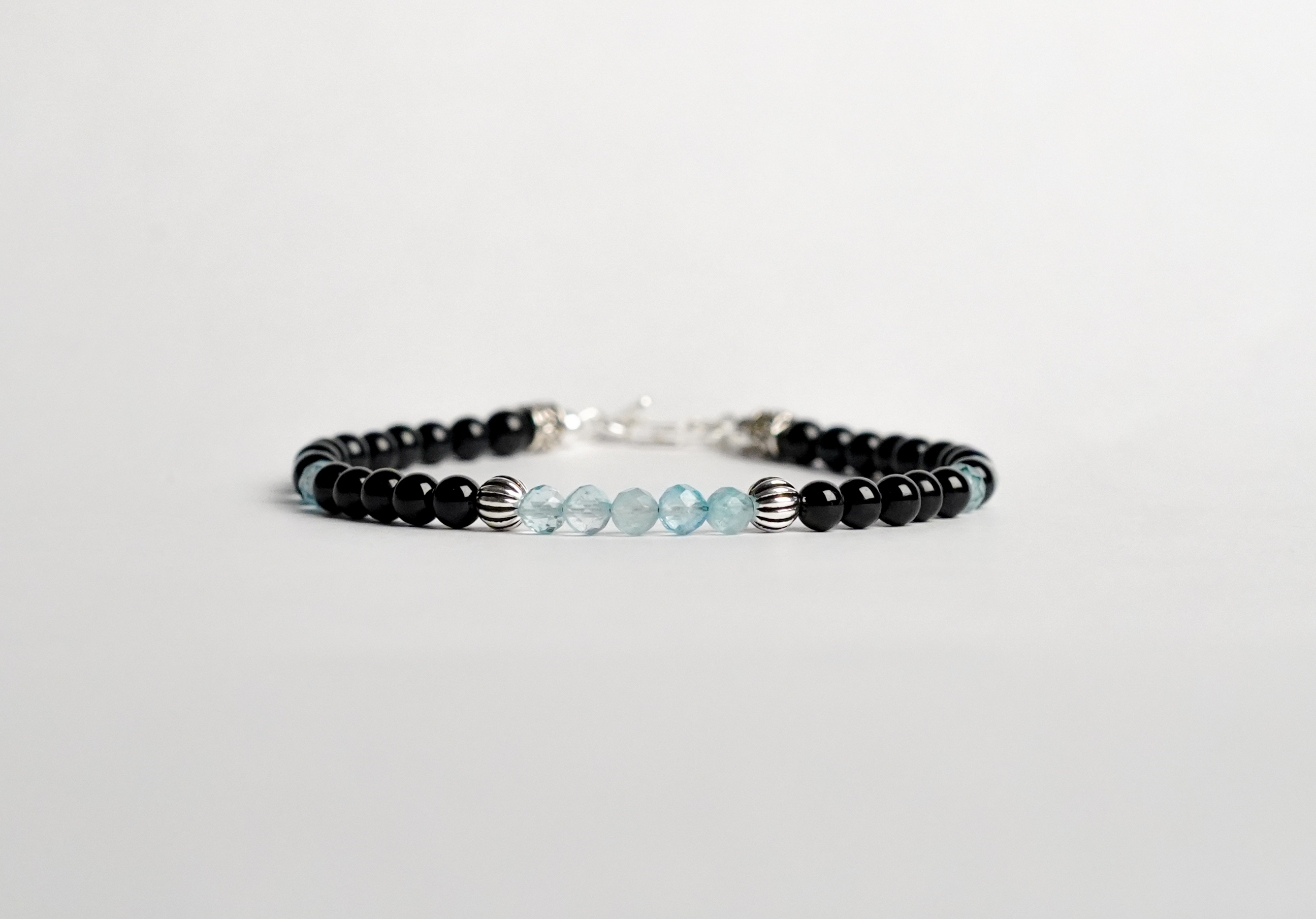 l bracciale è realizzato con perle di Tormalina nera, gemme di Topazio svizzero e rifinito con accenti in Argento sterling 925 e pratica chiusura a moschettone in Argento sterling 925.