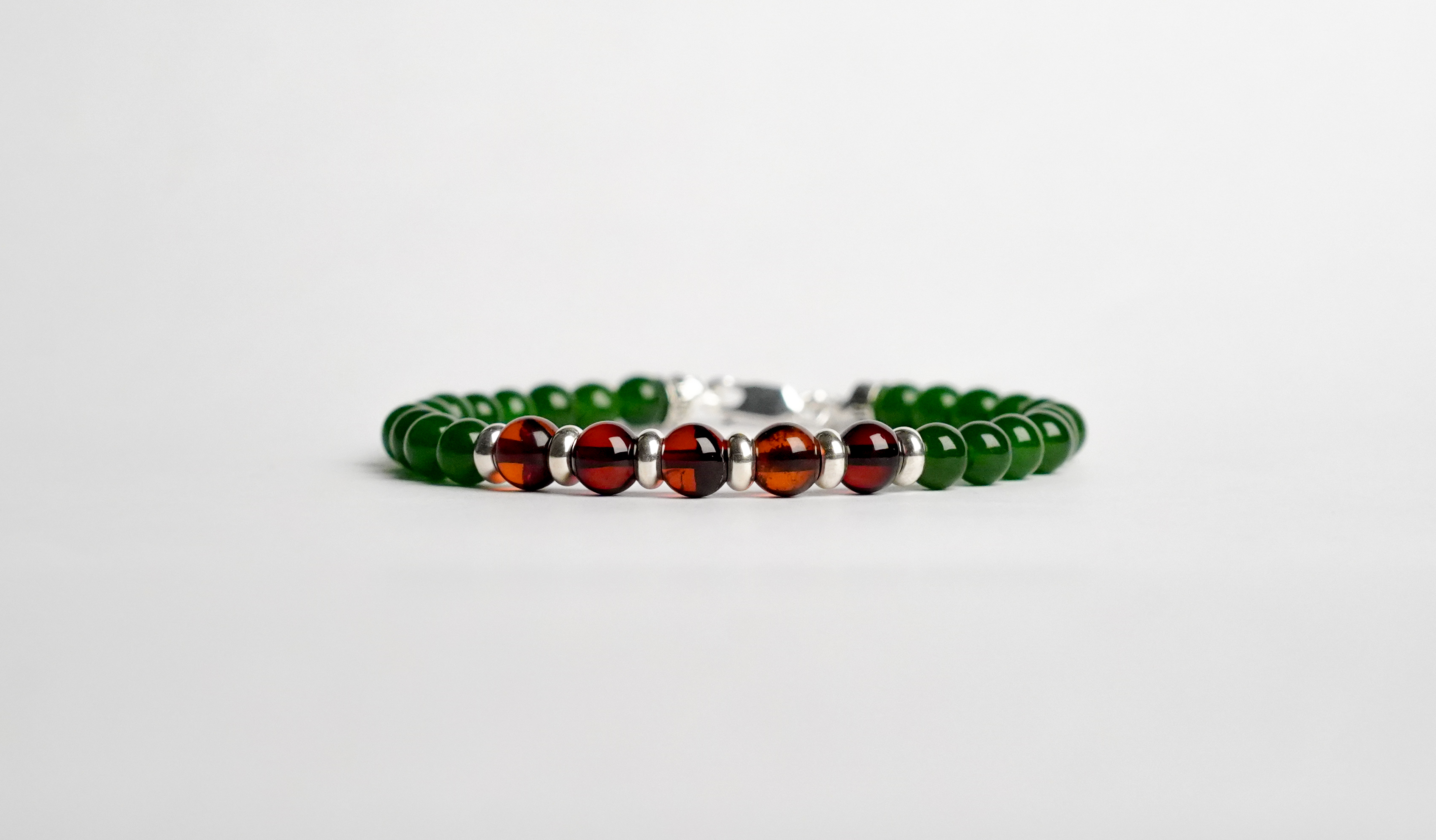 Il bracciale è realizzato con perle di Giada verde, Ambra baltica e rifinito con accenti in Argento sterling 925 e pratica chiusura a moschettone in Argento sterling 925.